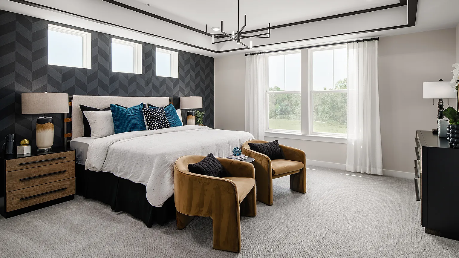 Owner's suite with king bed, accent chairs, and large windows at The Kincora Residence model home