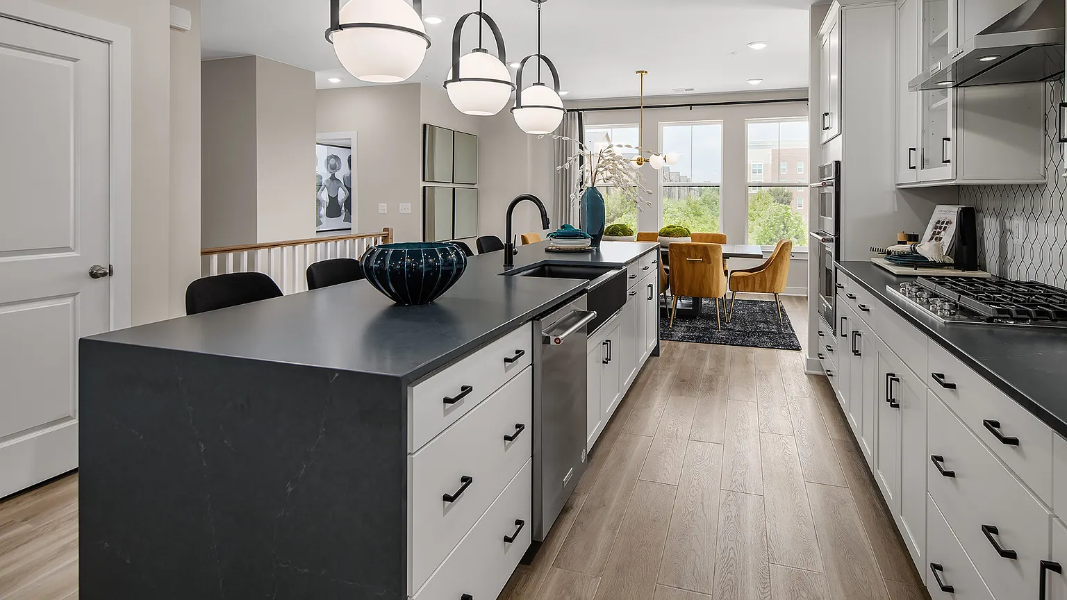 Kitchen with oversized island, dark counters, and pendant lighting at The Kincora Residence model home