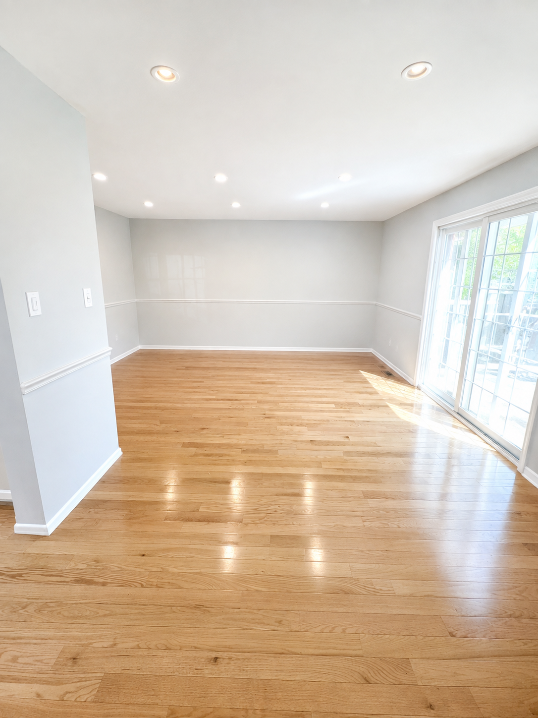 The Leeway Residence — Unfurnished living room with hardwood floors, chair rail, and sliding glass doors