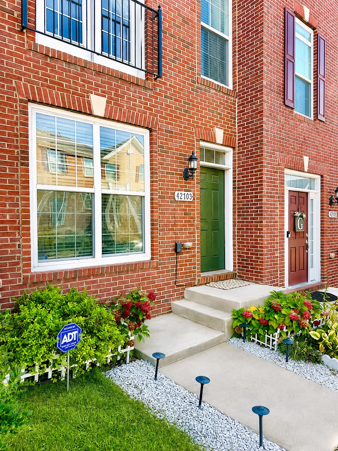 The Ashburn Residence — Brick townhome front entry with landscaped garden beds