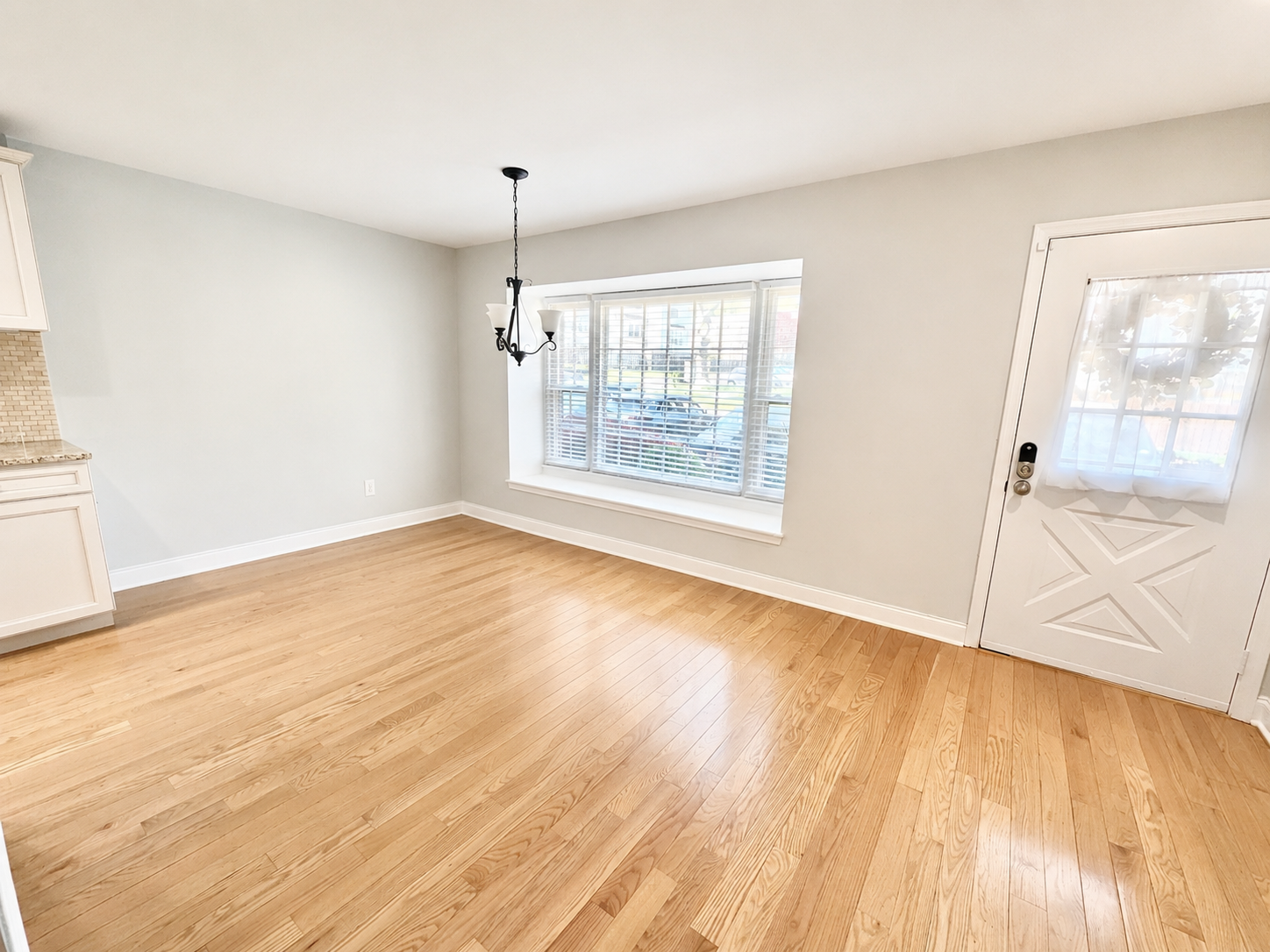 Unfurnished dining area with chandelier, bay window, and hardwood floors at The Leeway Residence