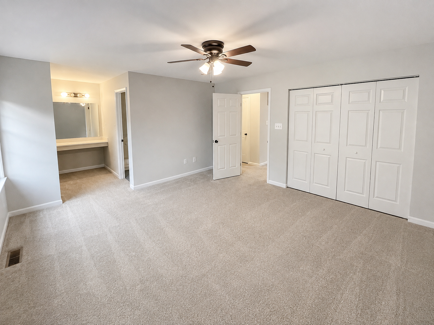 The Leeway Residence — Primary bedroom with ceiling fan, dressing area, and double closets