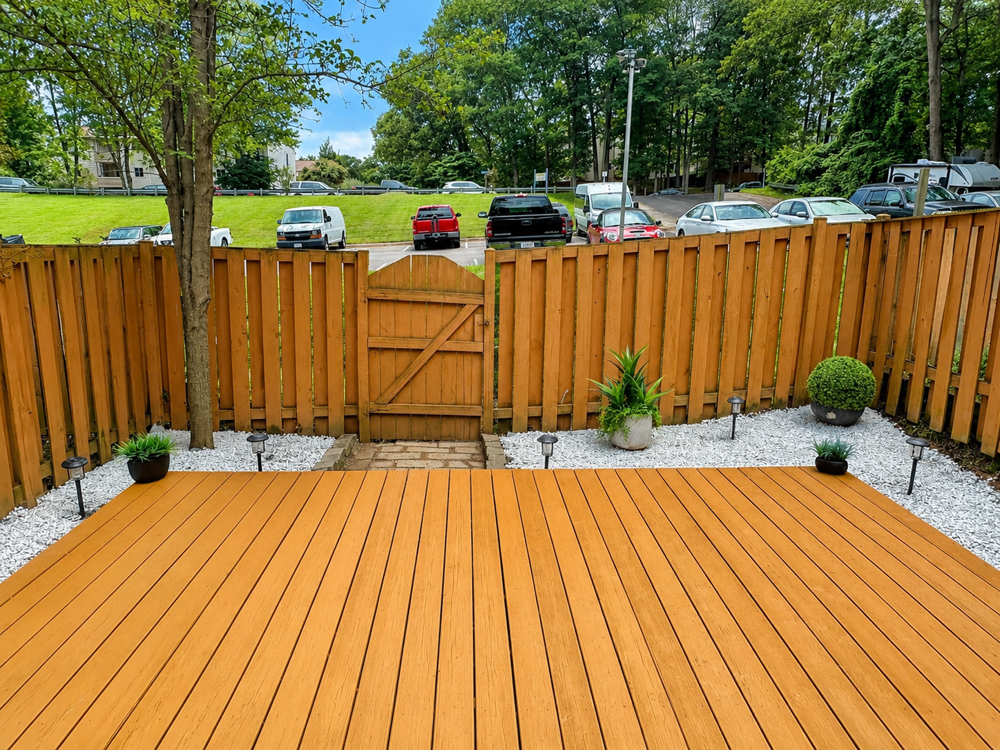 Spacious deck with wooden privacy fence, landscaped gravel beds, and backyard gate at The Leeway Residence