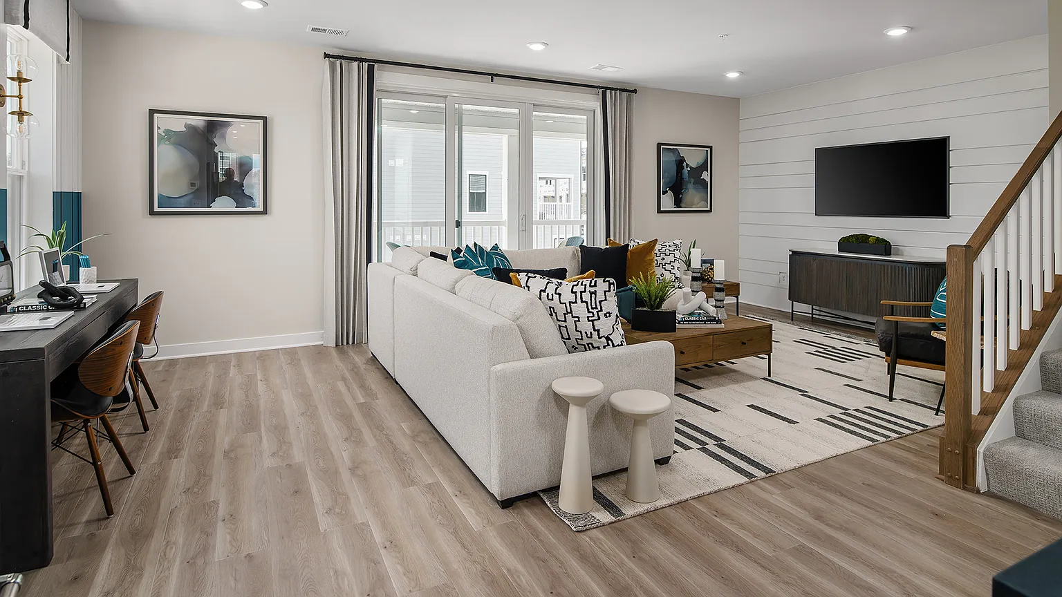 The Kincora Residence — Great room with sectional sofa, media wall, and access to the lanai at The Kincora Residence model home