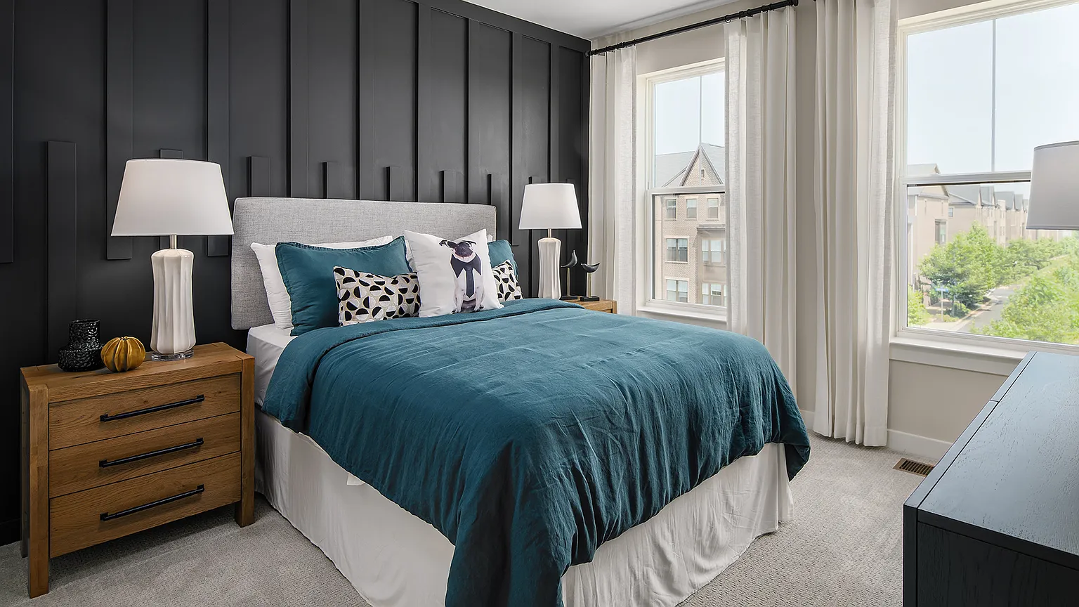 Secondary bedroom with dark accent wall, queen bed, and large windows at The Kincora Residence model home
