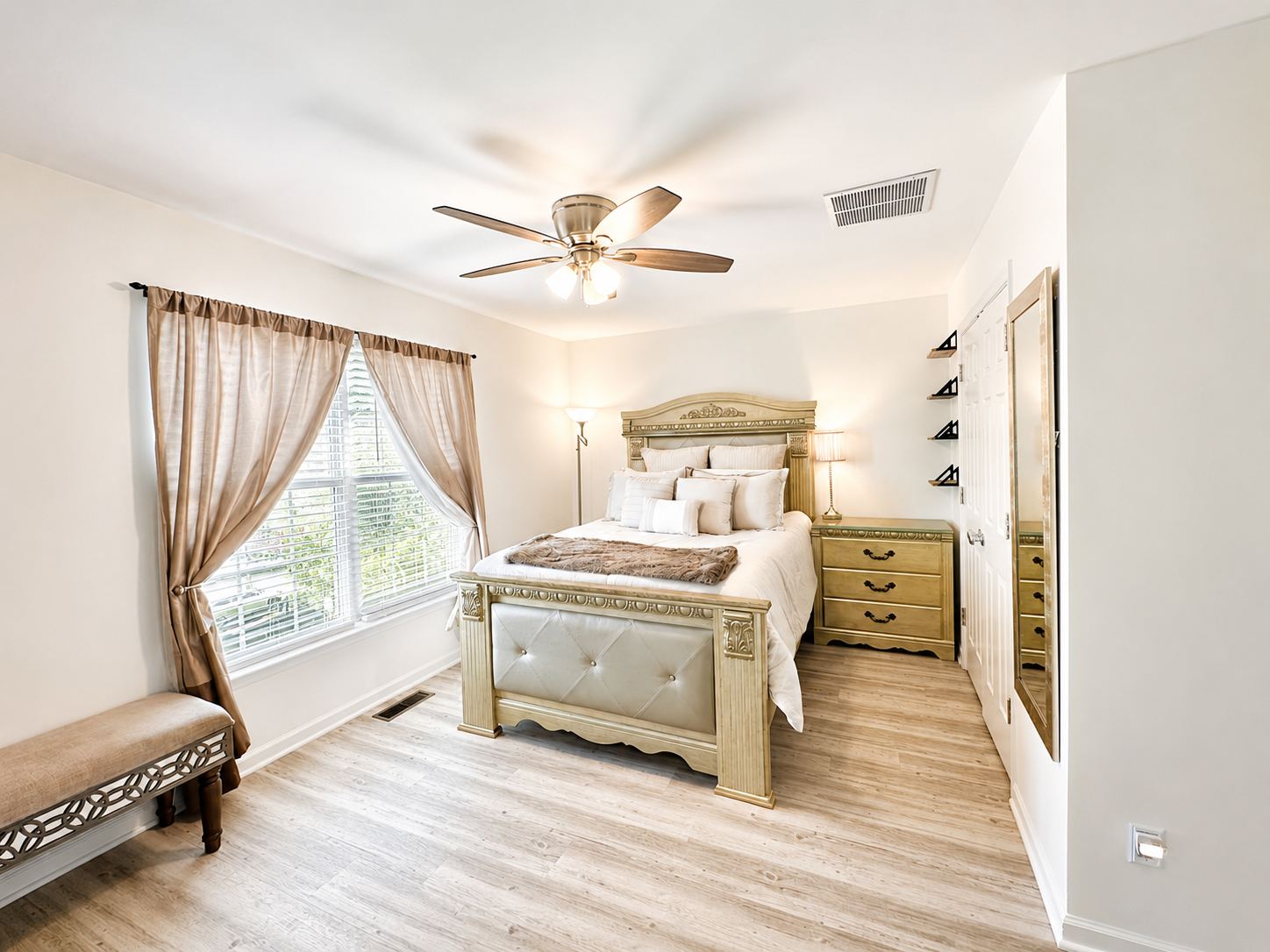 The Ashburn Residence — Furnished primary bedroom with carved wood bed frame and natural light
